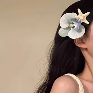 Detailed side view of a romantic orchid and starfish hair clip worn on long wavy hair