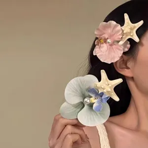 Detail view of a tropical orchid and starfish hair clip with a pearl accent on a model