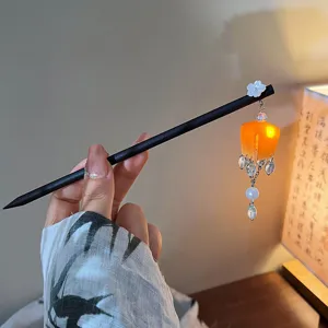 Close-up of a vintage hair stick featuring an orange palace lantern tassel design