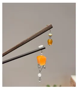 Close-up detail of traditional Chinese style wooden hairpins with orange lantern tassels.