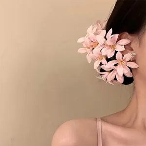 Dettaglio del fermaglio per capelli con fiori rosa indossato su un modello