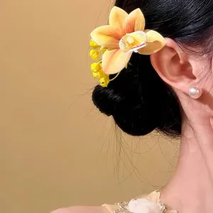 Bright yellow orchid flower hair clip for spring vacation styling on side hair