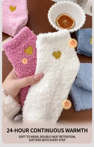 Nahaufnahme weicher weißer Korallenfleece-Socken mit Herzbestickung und rutschfesten Noppen.