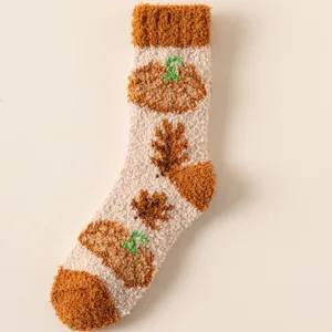 Nahaufnahme von warmen flauschigen Korallenfleece-Socken mit Kürbis- und Herbstblattmustern