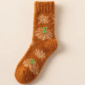 Nahaufnahme des weichen Kürbismusters auf dicken orangefarbenen Korallenfleece-Socken