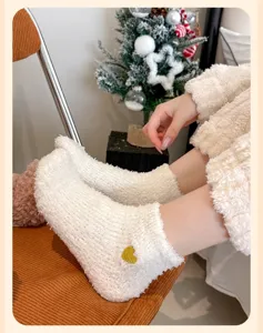 Kuschelige weiße Korallenfleece-Socken für Damen mit goldenem Herzaufnäher und weichem Plüsch.