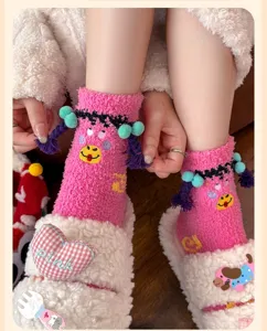 Detailansicht von rosa flauschigen Socken mit Cartoongesicht und weißen Plüschhausschuhen