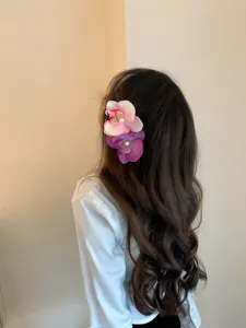 Ethereal orchid flower hair clips in pink and purple worn by a model in detail.