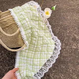 Primer plano de la textura de tela fruncida y el borde de encaje blanco de este pañuelo verde