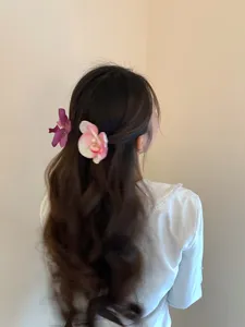 Elegant pink and purple orchid flower hair clips shown on a model's wavy hair.