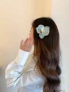 Model wearing an elegant light teal orchid hair clip with pearl detail on wavy hair