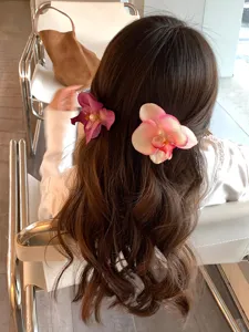 Detailed view of orchid flower hair clips styled on long wavy hair for a romantic look