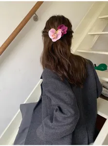 Detailed view of sweet pink and purple orchid flower hair clip worn on long wavy hair
