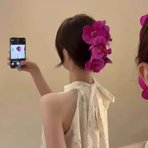 Elegant purple orchid flower hair clip worn by model for a romantic aesthetic look.