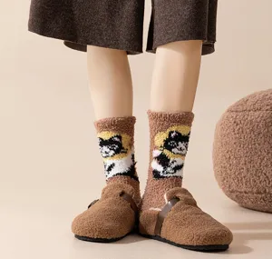 Nahaufnahme von flauschigen Korallenvlies-Socken mit Katzenmuster und braunen Hausschuhen