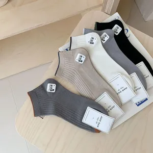 Close-up of assorted men's cotton boat socks in neutral tones on a wooden table