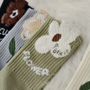 Macro view of soft floral texture and 'FLOWER' embroidery on thick winter socks.