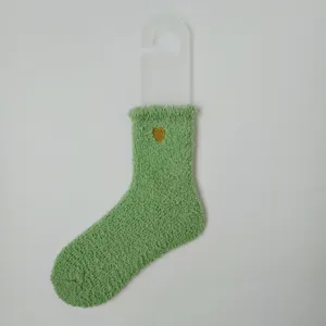 Nahaufnahme der grünen, flauschigen Korallenvlies-Socke mit goldenem Herz-Stick.