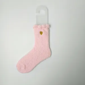 Detail einer rosa Korallenvlies-Socke mit einem goldenen Herz-Stickerei-Motiv.
