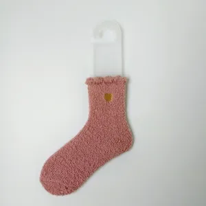 Detailansicht einer rosa dicken Korallenvlies-Socke mit goldenem Herz-Stickmuster.
