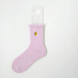 Detaillierte Ansicht einer rosa Korallenvlies-Socke mit goldener Herzstickerei.