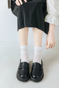 Primo piano di calzini bianchi con ruches in pizzo traforato per uno stile JK Lolita.