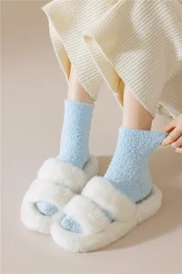 Primer plano de calcetines de vellón coral azul claro y zapatillas de felpa blancas.