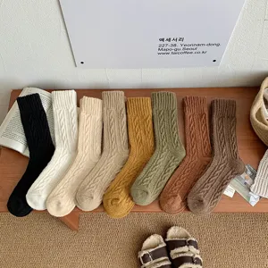 Close-up detail of eight colors vintage cable-knit thermal socks on a wooden bench