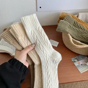 Macro view of thick cable-knit wool socks in neutral tones showing detailed texture