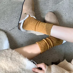 Close-up of ginger yellow cable knit cashmere slouch socks with winter clogs