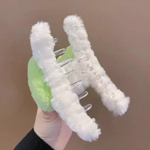 Vue détaillée de la texture en peluche douce blanche et verte d'une pince à cheveux panda