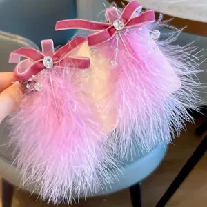 Détail de barrettes à cheveux éthérées en plumes roses avec nœuds en velours et perles.