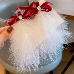 Détail de barrettes en plumes blanches avec nœuds en velours rouge et cristaux brillants