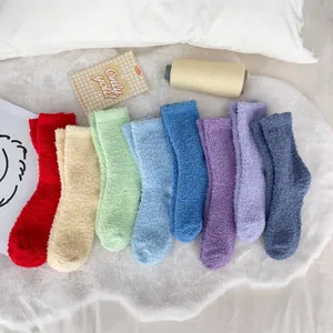 Variety of colorful coral fleece fuzzy socks arranged on a soft white rug