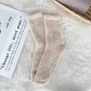 Detail shot of cozy beige coral fleece fuzzy sleep socks presented on a soft white rug