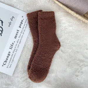 Detailed texture of brown coral fleece fuzzy sleeping socks on a soft white rug