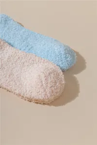 Detalle de calcetines de dormir de coralina suave en colores rosa y azul pastel.