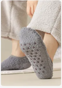 Primo piano dei gommini antiscivolo in silicone su calze in pile corallo grigie da uomo invernali.
