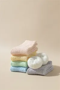 Primer plano de calcetines de dormir de forro polar coral suave en colores macarrón apilados
