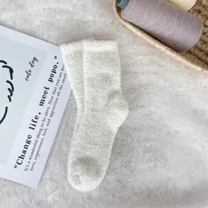 Macro view of cozy white coral fleece bed socks on a soft faux fur rug background