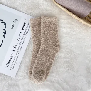 Detailed view of soft coral fleece sleep socks in light brown on a plush white rug