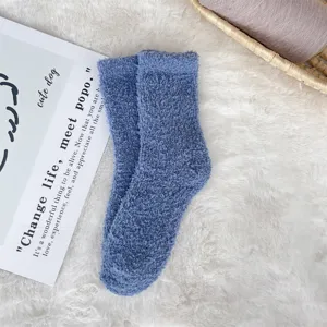 Close-up of cozy blue coral fleece fuzzy socks on white soft faux fur background