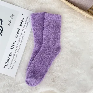 Soft purple coral fleece sleep socks displayed on a white plush rug for cozy winter wear.