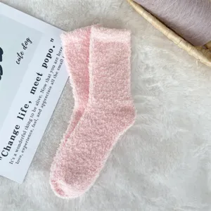 Detailed macro view of soft pink coral fleece fuzzy socks on a plush white background