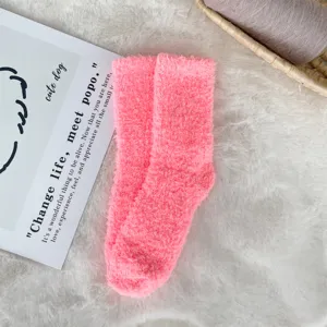Detail showing the soft texture of pink coral fleece fuzzy socks on a white fur rug