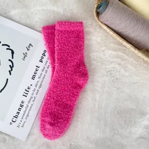 Soft bright pink coral fleece sleeping socks presented on a white faux fur rug