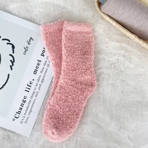 Close-up detail of soft pink coral fleece socks on a cozy white fluffy background