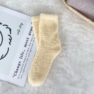 Close-up of soft cream white coral fleece fuzzy sleep socks with plush texture for winter
