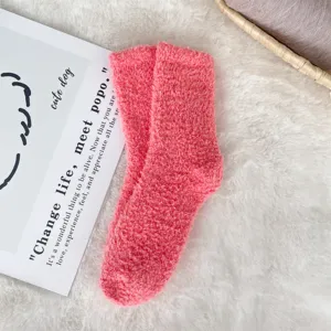 Detailed texture of cozy pink coral fleece sleep socks on a soft white plush background