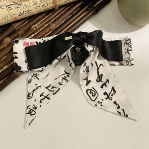 Détail d'une pince à cheveux avec nœud en ruban style peinture à l'encre chinoise.